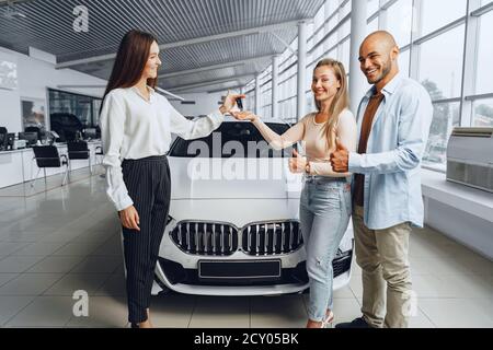 Venditore di automobili in un concessionario di automobili che ha un colloquio con clienti Foto Stock