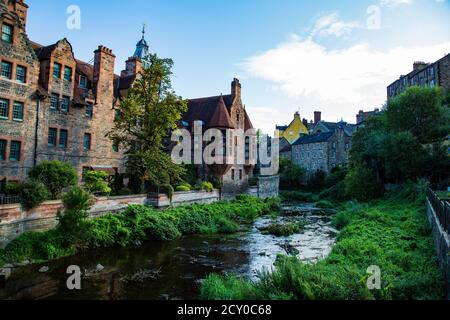 Fiume con vegetazione di fronte alla linea di pietra vecchia case Foto Stock