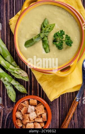 Zuppa cremosa di asparagi freschi e ingredienti su un tavolo di legno. Foto Stock