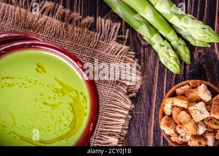 Zuppa cremosa di asparagi freschi e ingredienti su un tavolo di legno. Foto Stock