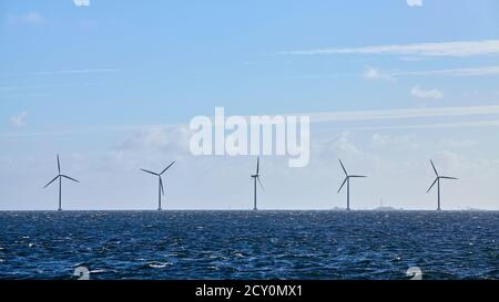 Fila di turbine eoliche offshore. Foto Stock