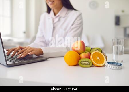 Frutta, un bicchiere d'acqua e un metro a nastro si trovano sul tavolo sullo sfondo di un nutrizionista Foto Stock