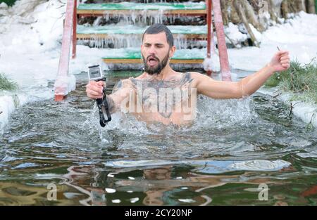 Uomo adulto che prende selfie dopo aver immerso in acqua ghiacciata durante la festa Epifania sul fiume Dnipro. 19 gennaio 2017. Kiev, Ucraina Foto Stock