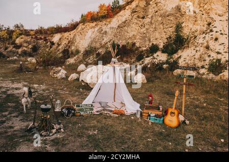 Scenario boho autunno con wigwam e decorazioni vintage all'aperto vicino alle montagne. Foto Stock