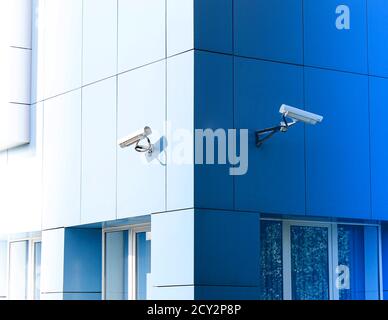 Due telecamere di sorveglianza sull'edificio vengono installate in direzioni opposte. Foto Stock