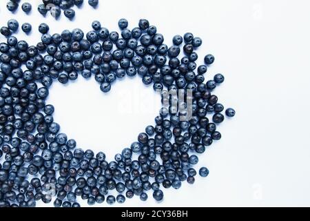 Forma a cuore fatta di mirtilli freschi su sfondo bianco. Cibo sano, frutti di bosco estivi. Concetto di cibo minimo. Piatto. Messa a fuoco selettiva. Spazio di copia. Foto Stock