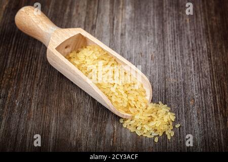 Riso in una paletta su sfondo di legno. Foto Stock