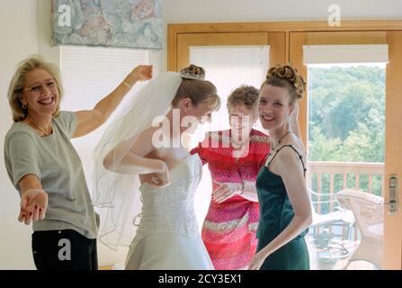 La madre e gli assistenti nuziali assistono la giovane sposa con il suo abito da sposa prima della cerimonia, USA 2001 Foto Stock