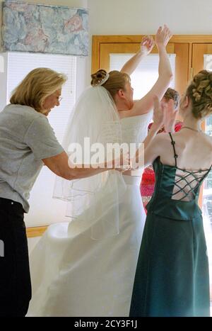 La madre e gli assistenti nuziali assistono la giovane sposa con il suo abito da sposa prima della cerimonia, USA 2001 Foto Stock
