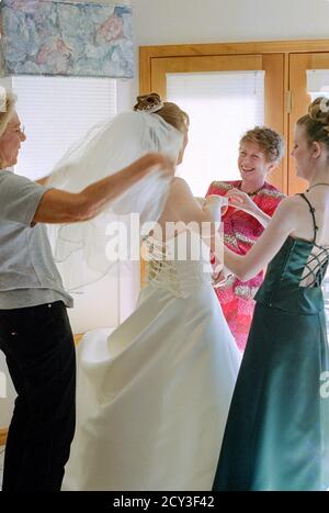 La madre e gli assistenti nuziali assistono la giovane sposa con il suo abito da sposa prima della cerimonia, USA 2001 Foto Stock