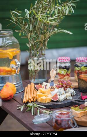 Tavolo con piatti italiani assortiti in giardino, delizioso spuntino per feste o picnic Foto Stock