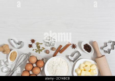 Ingredienti per cuocere i biscotti natalizi con pan di zenzero vista dall'alto su sfondo bianco di legno. Cibo panificio sfondo. Foto Stock