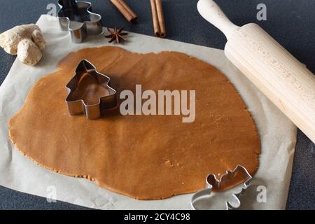 Preparazione di biscotti fatti in casa con pan di zenzero per le vacanze di Natale. Pasta speziata e taglierine in diverse forme natalizie. Foto Stock