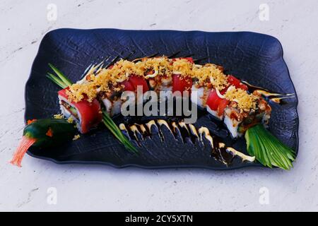 il sushi giapponese del drago rotola in un piatto nero Foto Stock