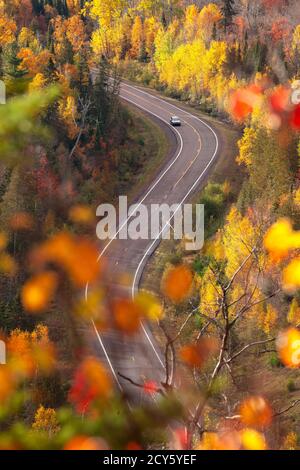 Vista ad alto angolo di un'auto su una strada in curva Da alberi in colore autunnale nel nord del Minnesota Foto Stock