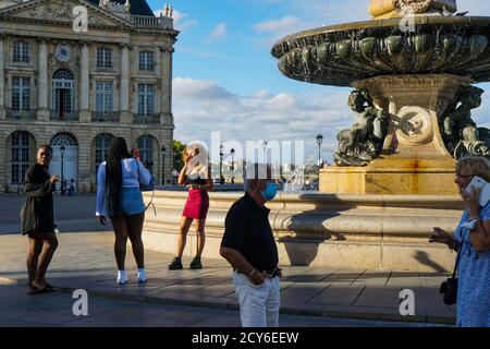 Bordeaux - 08/27/2020: Turisti che scattano foto e telefonano vicino alla fontana in Place de la Bourse Foto Stock