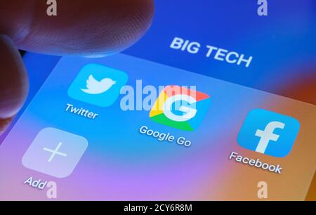 Google, Facebook, Twitter app visualizzate sullo schermo e sfocato con il dito puntato verso di loro. Foto Stock