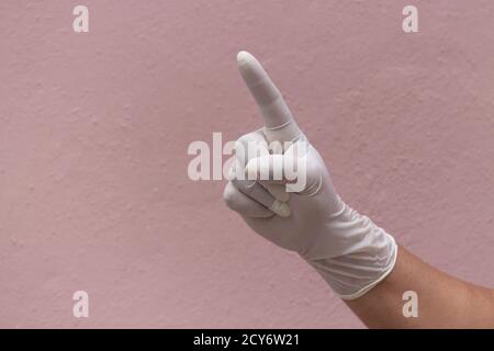 Mano di una persona in un guanto di plastica bianca che punta con l'indice Foto Stock