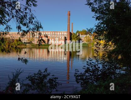 Un xix secolo mulino tessile è stato rinnovato per un uso moderno, visto riflesso nel fiume vicino a Exeter, New Hampshire Foto Stock