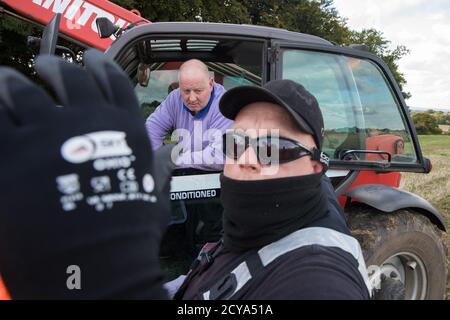 Aylesbury vale, Regno Unito. 1 ottobre 2020. Un Bailiff della squadra nazionale di viction ostruisce la macchina fotografica di photographerÕs come un coltivatore in un movimentatore telescopico posizionato su terra non obbligatoriamente acquistato da HS2 Ltd chiede chiarimento circa perchè una recinzione sta erigendo attraverso il suo campo durante lo sfratto degli attivisti anti-HS2 da un campo di protezione della fauna selvatica in Antico bosco a JonesÕ Hill Wood. Circa 40 attivisti ambientali e residenti locali, alcuni dei quali vivono in case di alberi di fortuna, erano presenti durante gli sfratti a JonesÕ Hill Wood, che aveva servito come uno dei numerosi campi di protesta allestiti lungo Foto Stock