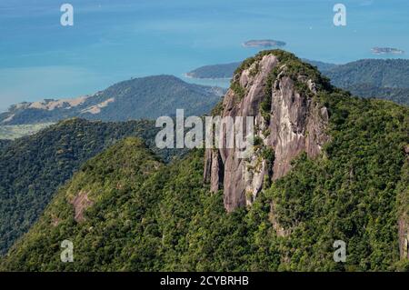 Vista e dettaglio più ravvicinati della cima della formazione rocciosa coperta dalla vegetazione verde di Serra do Mar con la costa della baia di Carioca sullo sfondo. Foto Stock