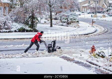 A est di Hannover, NJ - Nov 2014 - Uomo utilizza lo spalaneve per cancellare il suo marciapiede anteriore Foto Stock