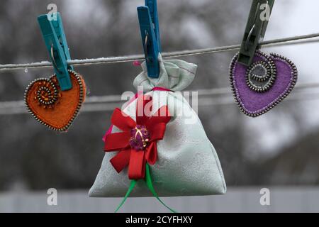 Giorno di San Valentino, prodotti fatti a mano da feltro, borsa regalo e due cuori di feltro appendere su abiti su un filo per asciugare i vestiti Foto Stock