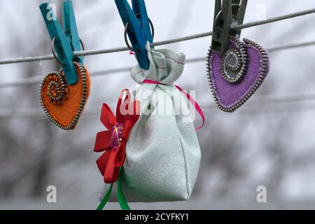 Giorno di San Valentino, prodotti fatti a mano da feltro, borsa regalo e due cuori di feltro appendere su abiti su un filo per asciugare i vestiti Foto Stock