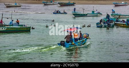 Puerto Lopez, Ecuador - 12 settembre 2018 - una piccola barca di gara arriva fino alla spiaggia da una barca da pesca Foto Stock