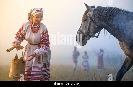 Giovane donna attraente una camicia ricamata beve un cavallo Foto Stock