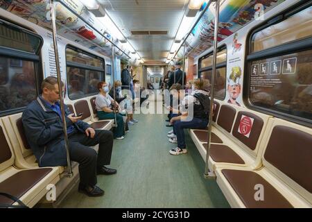 Mosca, Russia - 29 agosto 2020: Fotografia di persone in carrozza di metropolitana. Qualcuno seduto, utilizzando lo smartphone. Indossare / indossare / usare protectiv Foto Stock