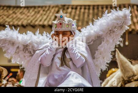 Latacunga, Ecuador - 22 settembre 2018 - ragazza in costume di angelo tiene i suoi orecchi contro i rumori del Mama Negra parade Foto Stock