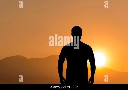 Silhouette di un uomo in piedi di fronte alle montagne durante bellissimo tramonto Foto Stock