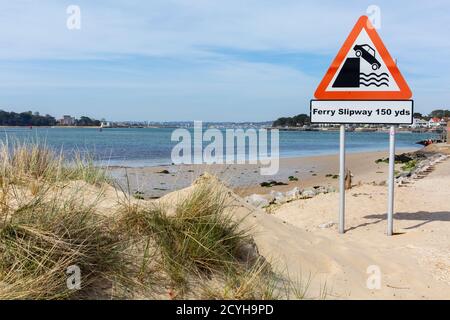 Una vista attraverso Poole Harbour con Brownsea Island, Brownsea Castle e la città di Poole in lontananza con un cartello in primo piano che dice traghetto Foto Stock