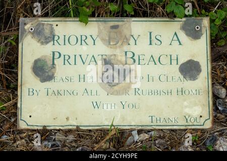 Un vecchio segno che dice che questa è una spiaggia privata e che chiede ai visitatori di portare la loro casa spazzatura con loro a Priory Beach sull'Isola di Wight. 2 Foto Stock