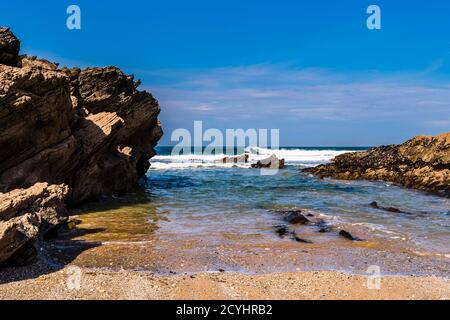 Onde che si infrangono e surfista solista vicino a Fistral Beach, Newquay, Cornovaglia, Regno Unito Foto Stock