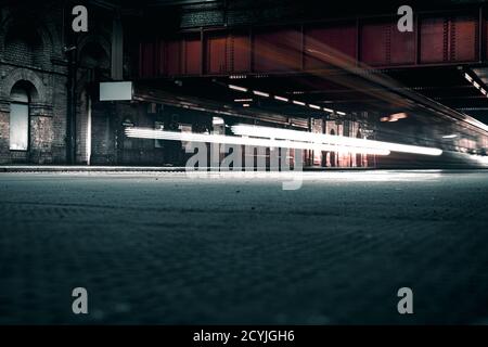 Riprese cinematografiche a lunga esposizione della rete ferroviaria sotterranea in Londra in una stazione all'aperto con luci luminose Foto Stock