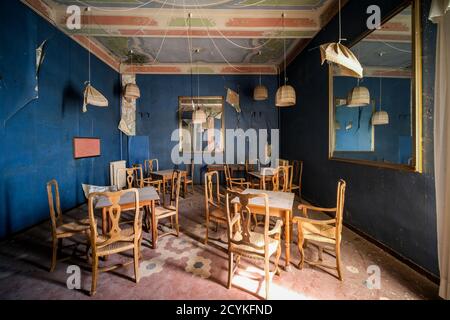 sala da pranzo con tavolo e sedie in legno in casa abbandonata Foto Stock