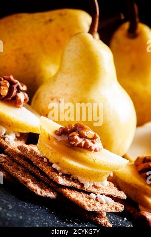 Antipasto da pane scuro croccante, formaggio di cottage, noci e pere con miele, sfondo scuro, fuoco selettivo Foto Stock