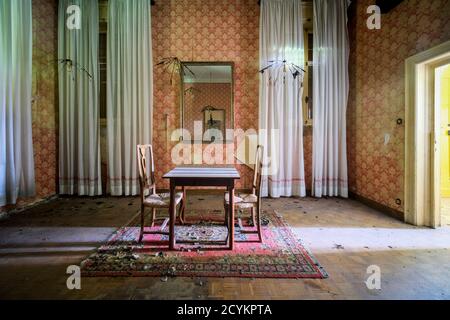 sala da pranzo con tavolo e sedie in legno in casa abbandonata Foto Stock