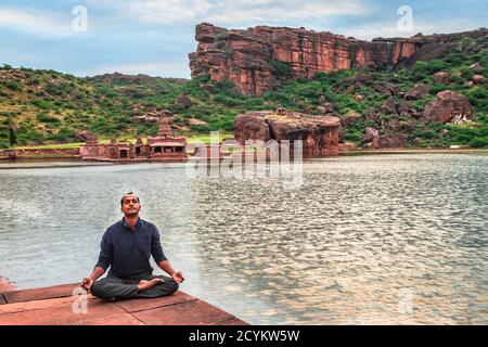 uomo che medita sulla riva del lago con sfondo di montagna all'alba L'immagine mostra la bellezza del Tempio di Bhutanatha sul Coste di Agastya Tirrha a Bada Foto Stock