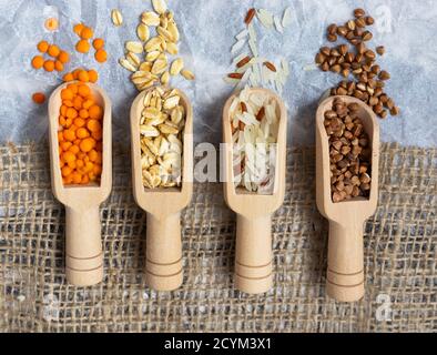 Sessole in legno con diverse groat: Farina d'avena, lenticchie, grano saraceno e riso Lay piatto Foto Stock