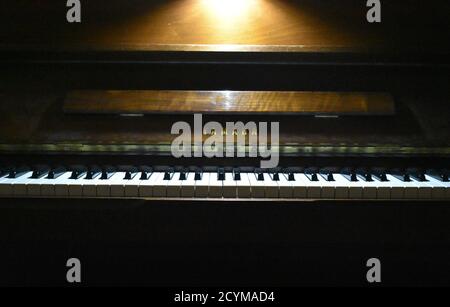 Un pianoforte con una luce sulla parte superiore che illumina i tasti. Foto Stock