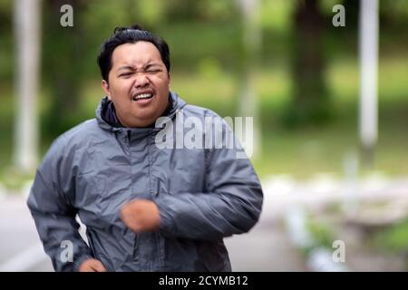 Ritratto dell'uomo grasso che si sente stanco di fare jogging nel parco. Ha bisogno di perdere peso e ottenere il corpo perfetto. Foto Stock