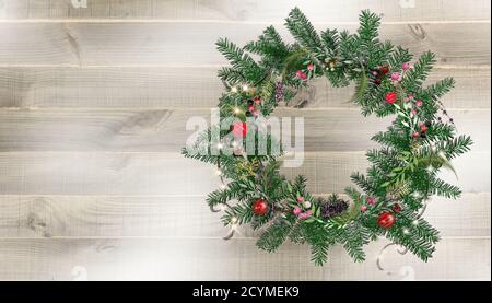 Corona di Natale con ornamenti festosi su rustico sfondo di legno. Illustrazione 3D realistica. Spazio di copia. Foto Stock