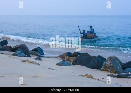 Pescatori indiani sulla barca da pesca che raccoglie sardine in cesto appena pescato dal profondo Kerala India. Foto Stock