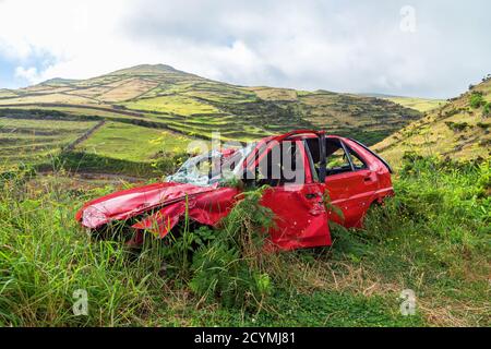 Un'auto rossa abbandonata è rimasta nella zona di montagna selvaggia Foto Stock