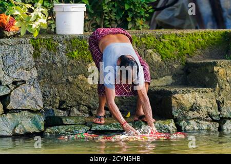 Donna che lava i vestiti in modo tradizionale sulle acque posteriori in questo distretto dei corsi d'acqua; Alappuzha (Alleppey), Kerala, India Foto Stock