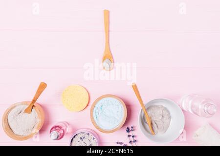 Flat Lay prodotti cosmetici per la spa fatti in casa argilla, olio aromatico, maschere facciali su sfondo rosa. Foto Stock