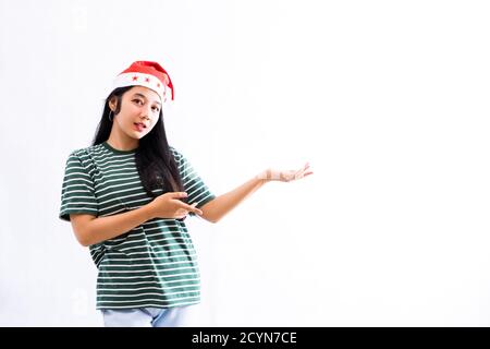 Ritratto di giovane donna asiatica che indossa un cappello di santa e. indossare abiti casual presenta uno spazio per la copia sulla sinistra con uno sfondo bianco isolato Foto Stock